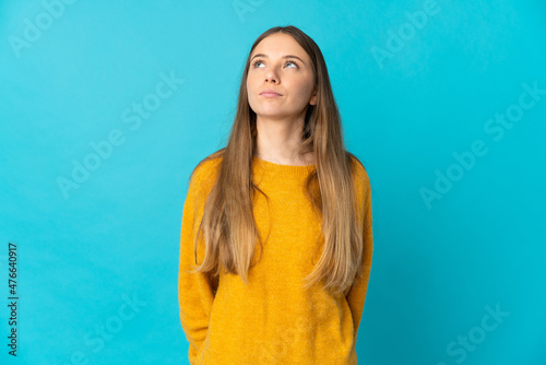 Young Lithuanian woman isolated on blue background and looking up