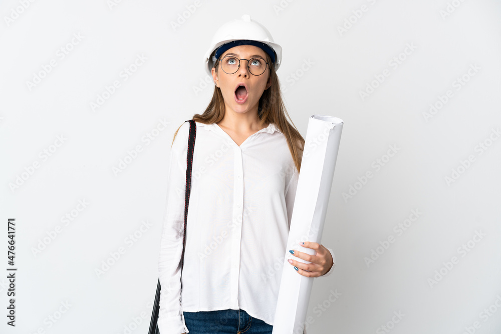 Young Lithuanian architect woman with helmet and holding blueprints isolated on white background looking up and with surprised expression Young Lithuanian architect woman with helmet and holding blueprints isolated on white background looking up and with surprised expression