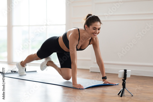 Young woman stretching leg in front of smartphone