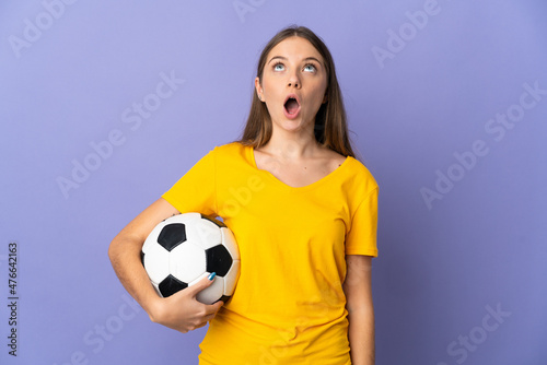Young Lithuanian football player woman isolated on purple background looking up and with surprised expression © luismolinero