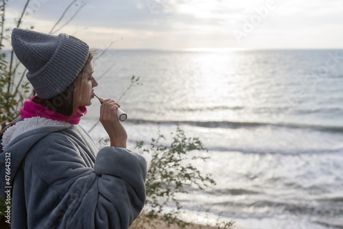 Woman brushing her teeth against the background of the sea sunrise