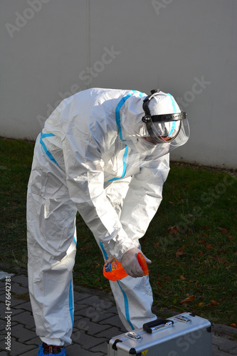 Mężczyzna w kombinezonie ochronnym podczas pandemii Covid-19 dezynfekuje sprzęt medyczny.