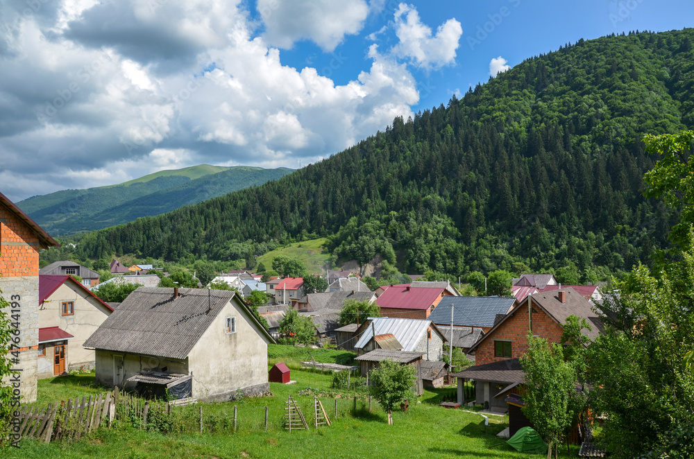 Colorful summer rural landscape with houses in the valley and mountains on background. Lifestyle in the Carpathian village Kolochava. Carpathians, Ukraine Colorful summer rural landscape with houses in the valley and mountains on background. Lifestyle in the Carpathian village Kolochava. Carpathians, Ukraine