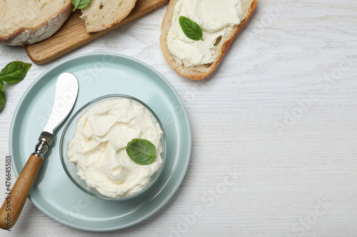 Tasty cream cheese with basil and fresh bread on white wooden table, flat lay. Space for text
