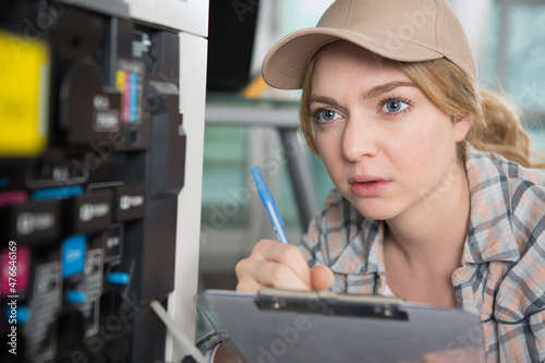 closeup of a woman fixing a photocopier during maintenance