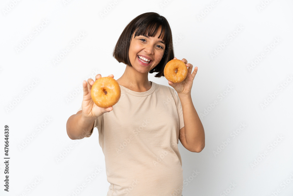 Young mixed race pregnant woman isolated on white background holding donuts with happy expression Young mixed race pregnant woman isolated on white background holding donuts with happy expression