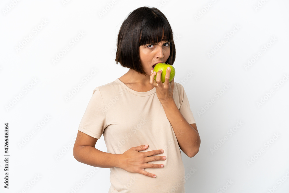 Young mixed race pregnant woman isolated on white background eating an apple Young mixed race pregnant woman isolated on white background eating an apple