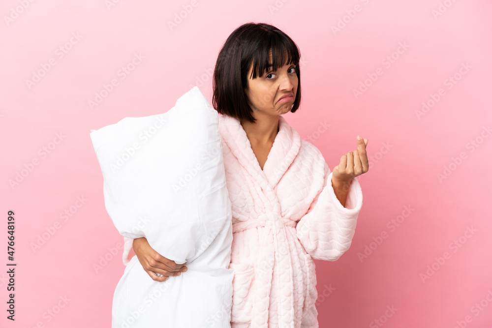Pregnant woman in pajamas isolated on pink background making money gesture Pregnant woman in pajamas isolated on pink background making money gesture