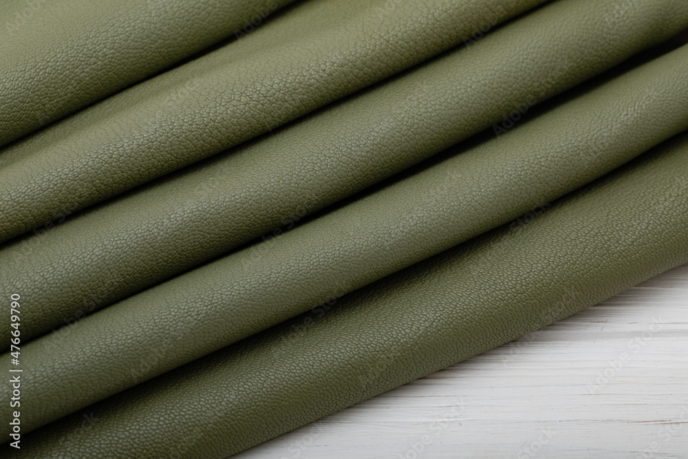 Fototapeta premium khaki green folded natural textured cow leather on the wooden table 