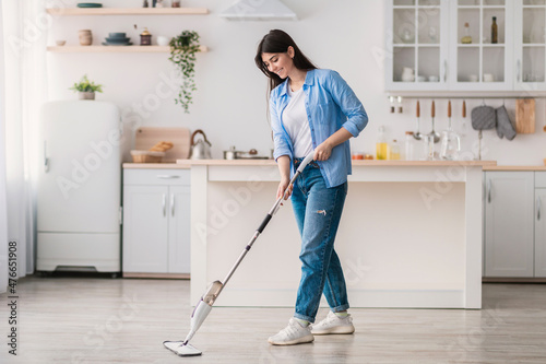 Fotografie Portrait of woman cleaning floor in kitchen with spray mop