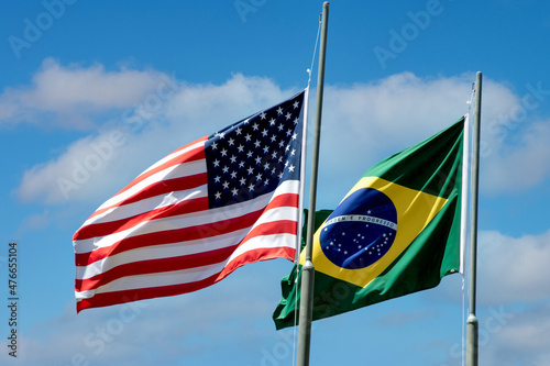 Flags of the United States of America (USA) and Brazil raised. Blue sky in the background photo