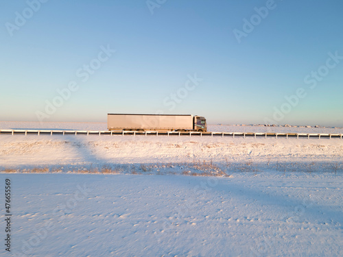 Lorry truck on the road surrounded by winter fields.
