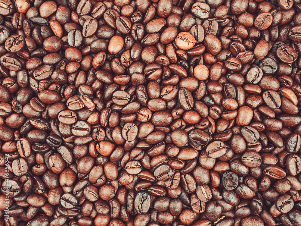 Naklejka premium Roasted coffee beans background under electric light overhead view.