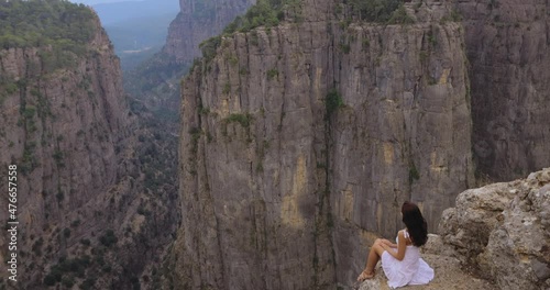 Tourist woman in white dress sitting on the edge of the mountaing cliff against the backdrop of a gorge. Amazing Tazi Canyon ,Bilgelik Vadisi in Manavgat, Antalya, Turkey. Greyhound Canyon, Wisdom photo