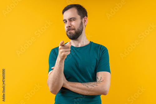 Photo Portrait of attractive young bearded man winking and pointing with his index finger directly to the camera