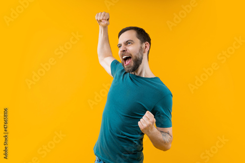 Foto Young euphoric bearded man celebrating money win at bookmaker's after betting at favourite team, screaming yes and making winner's gesture clenching his fist