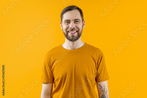 Portrait of handsome smiling bearded guy posing isolated over bright colored yellow background