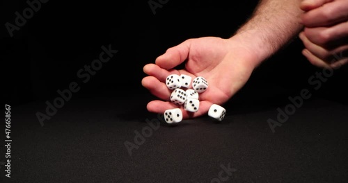 Rolling White dice on a black background. Hand dropping dice. Macro shot, side-view camera tracking. 4k