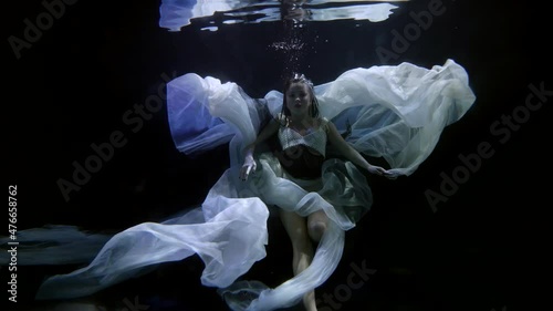 romantic stunning woman in white dress is floating underwater, enigmatic female figure