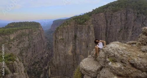Tourist woman in white dress climbing to the edge of the mountaing cliff against the backdrop of a gorge. Amazing Tazi Canyon ,Bilgelik Vadisi in Manavgat, Antalya, Turkey. Greyhound Canyon, Wisdom photo