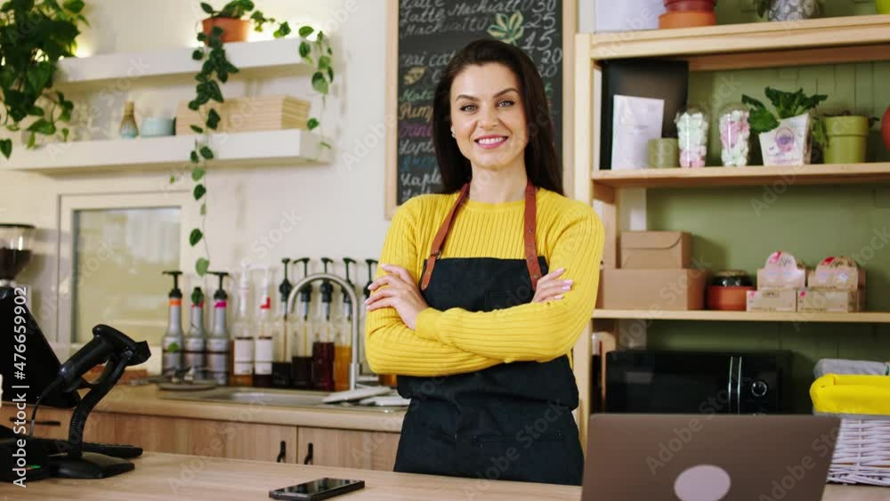 Concept of small business beautiful mature woman barista posing in front of the camera in the coffee shop she crossing hands and looking straight to the camera Concept of small business beautiful mature woman barista posing in front of the camera in the coffee shop she crossing hands and looking straight to the camera
