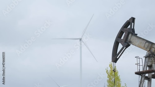 Oil pumps in work with electric windmill on background
