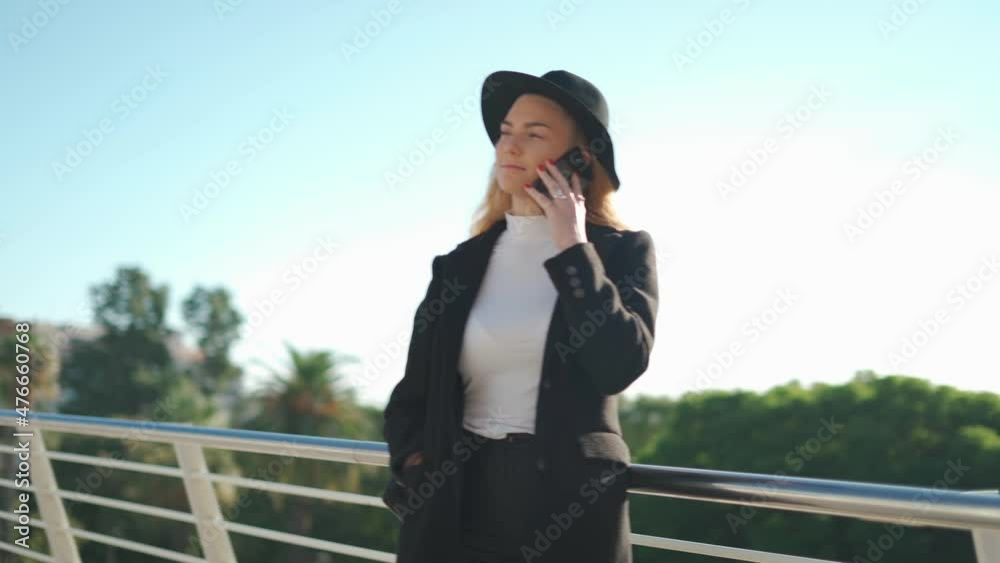 Young woman talking on mobile phone on bridge in sunlight Young woman talking on mobile phone on bridge in sunlight