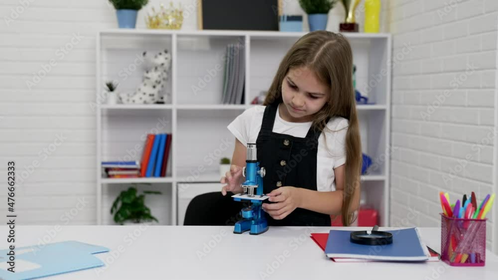 busy schoolgirl using microscope on biology lesson, education