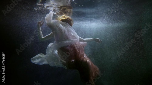 underwater shot with amazing beautiful young woman in silk flowing dress, grace and beauty