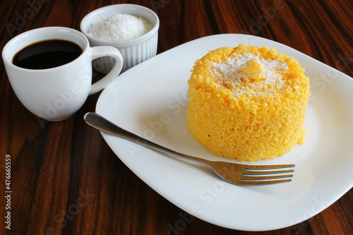 Corn couscous with coconut grated, cup of coffee on the wooden table.