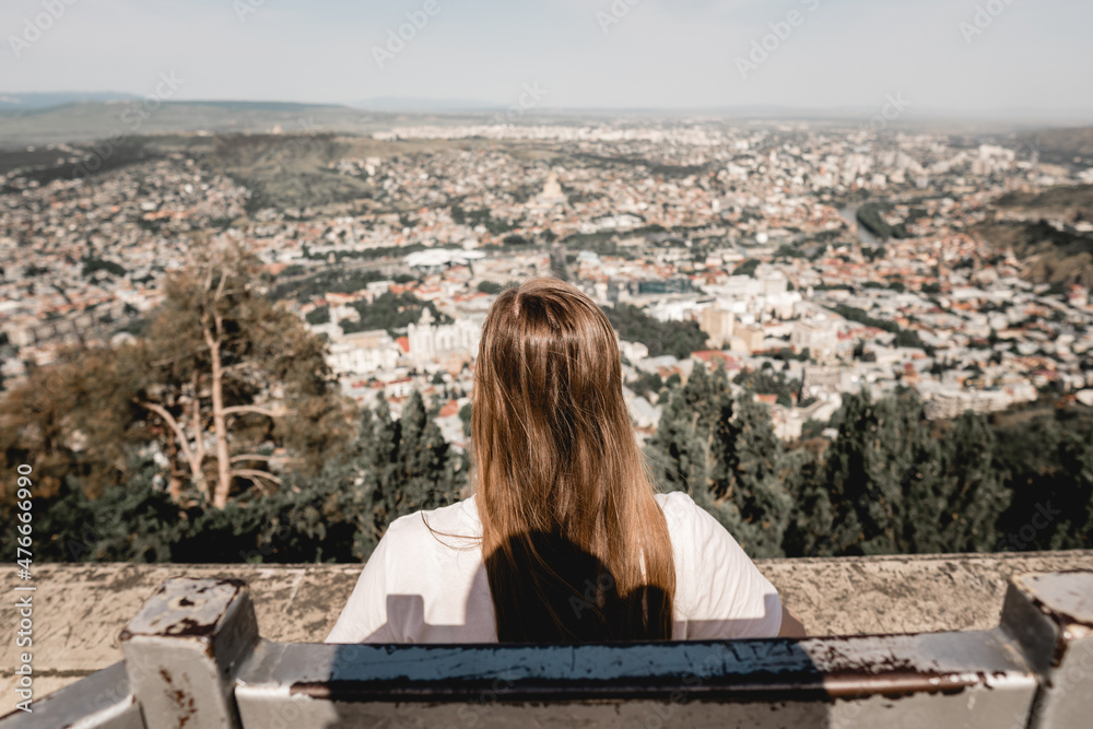 Young Woman sitting on top of  with city view 