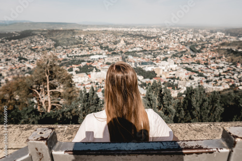 Fototapeta Naklejka Na Ścianę i Meble -  Young Woman sitting on top of  with city view 