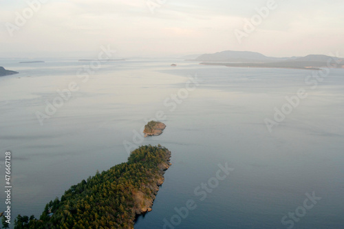 Aerial photograph of Blunden Islet with the San Juan Islands in the distance. Blunden Islet is part of the Gulf Islands National Park Reserve of Canada, South Pender Island, British Columbia, Canada photo