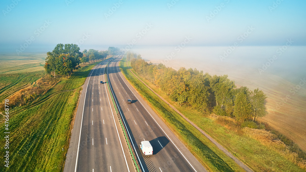 Sunny Magical autumn foggy morning. Aerial view of highway with cars.