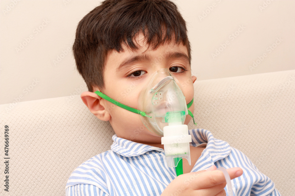 Little boy making inhalation with nebulizer at home. Asthma attack concept