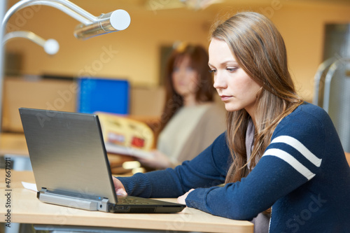 young student girl working with laptop in library