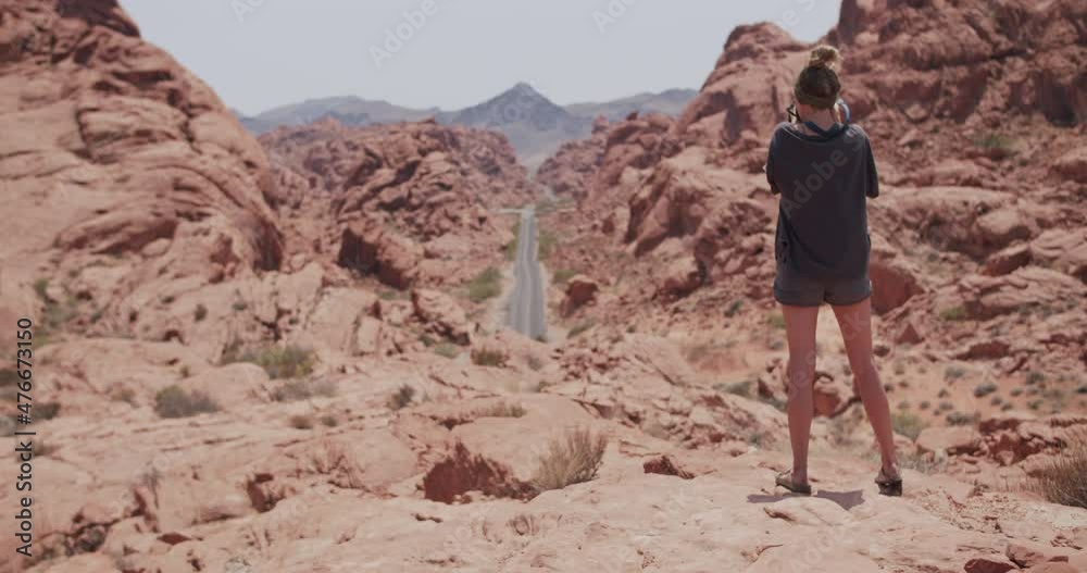 Young female photographer takes a picture of a long straight road in valley of fire state park in Nevada Young female photographer takes a picture of a long straight road in valley of fire state park in Nevada
