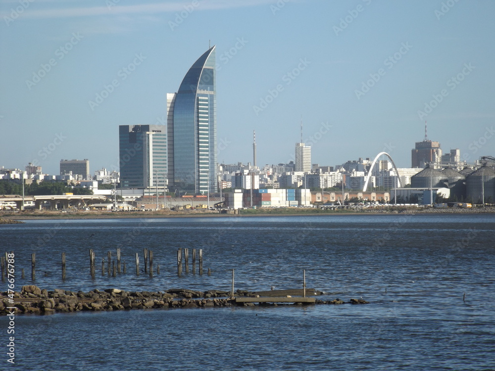 Uruguay port skyline. Buildings of the port area on the coast of the bay of Montevideo. Antel Tower, Palacio Salvo, cranes, customs, containers and ships in the water at sunset.
