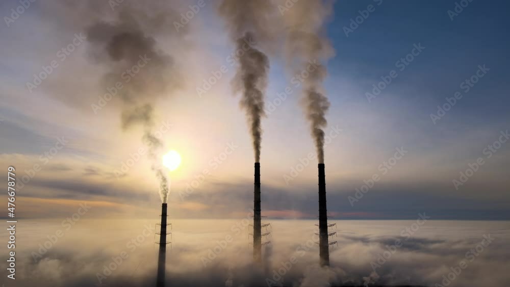 Aerial view of coal power plant high pipes with black smoke moving up polluting atmosphere at sunset Aerial view of coal power plant high pipes with black smoke moving up polluting atmosphere at sunset