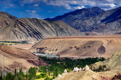 Rocky landscape of Ladakh with green valley in the middle, play of light and shadowJammu and Kashmir, Leh, India