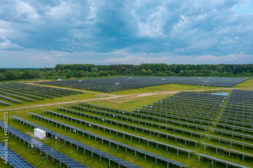 Huge solar power plant to use solar energy in a picturesque green field in Ukraine. Aerial panoramic drone shot