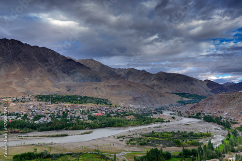Top view of Indus river and Kargil City valley with Himalayan mountains and blue cloudy sky in background, Leh, Ladakh, Jammu and Kashmir, India