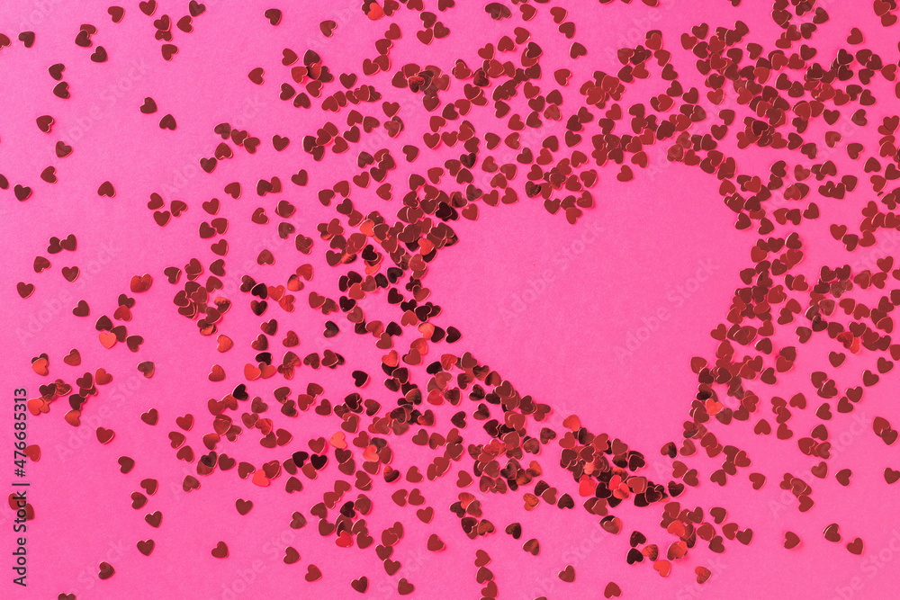 A creative heart made of a large number of small shiny hearts on a pink background. The concept of Valentine's Day.