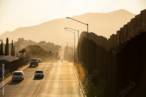 Tecate, Baja California, Mexico - September 14, 2021: Late afternoon sun shines on the USA Mexico border wall as it winds through Tecate. photo