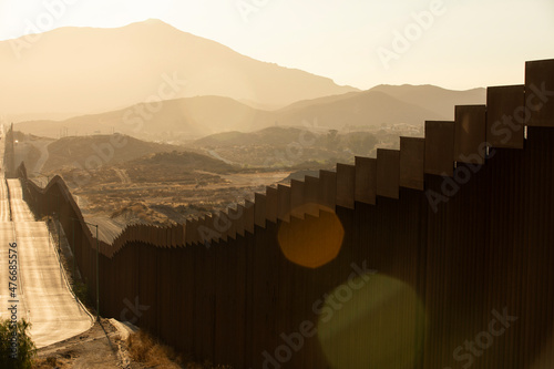 Tablou pe pânză Tecate, Baja California, Mexico - September 14, 2021: Late afternoon sun shines on the USA Mexico border wall as it winds through Tecate