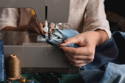 Bild auf Leinwand Seamstress using sewing machine for hemming jeans