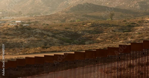Tecate, Baja California, Mexico - September 14, 2021: Late afternoon sun shines on the USA Mexico border wall as it winds through Tecate.