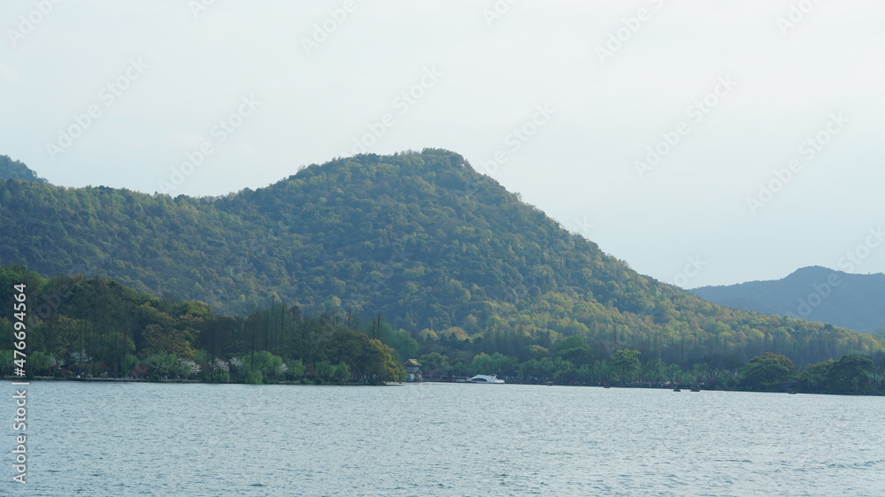The beautiful lake landscapes in the Hangzhou city of the China in spring with the peaceful lake and fresh green mountains The beautiful lake landscapes in the Hangzhou city of the China in spring with the peaceful lake and fresh green mountains