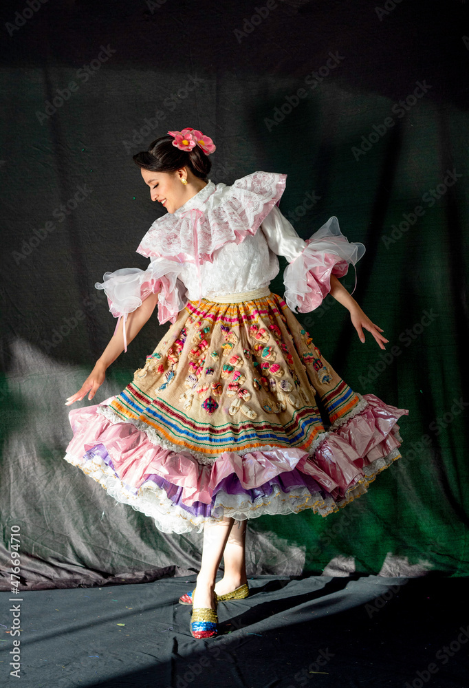 Portrait of Colombian woman dancer in Huila folklore costume dress with a white shirt, colorful hand sewed dress in the studio with black drop 