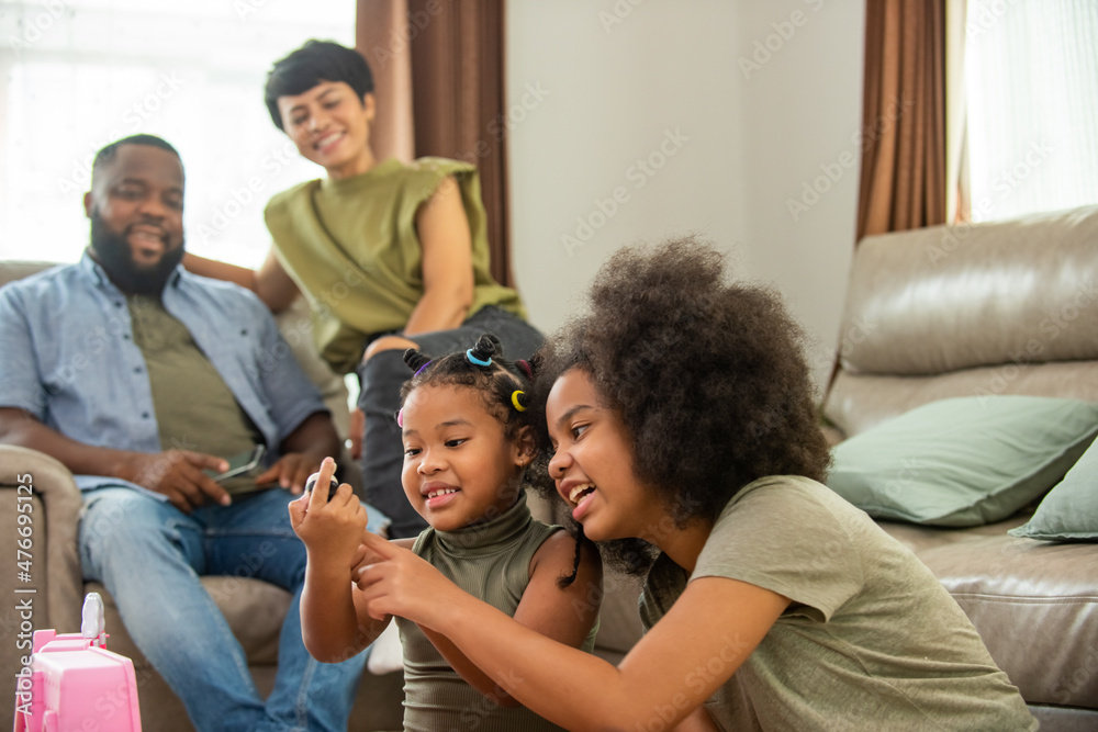 African family spending time together at home. Cute child girl kid sibling playing toy together on the floor in living room. Little daughter enjoy and having fun leisure activity with parents at home. African family spending time together at home. Cute child girl kid sibling playing toy together on the floor in living room. Little daughter enjoy and having fun leisure activity with parents at home.